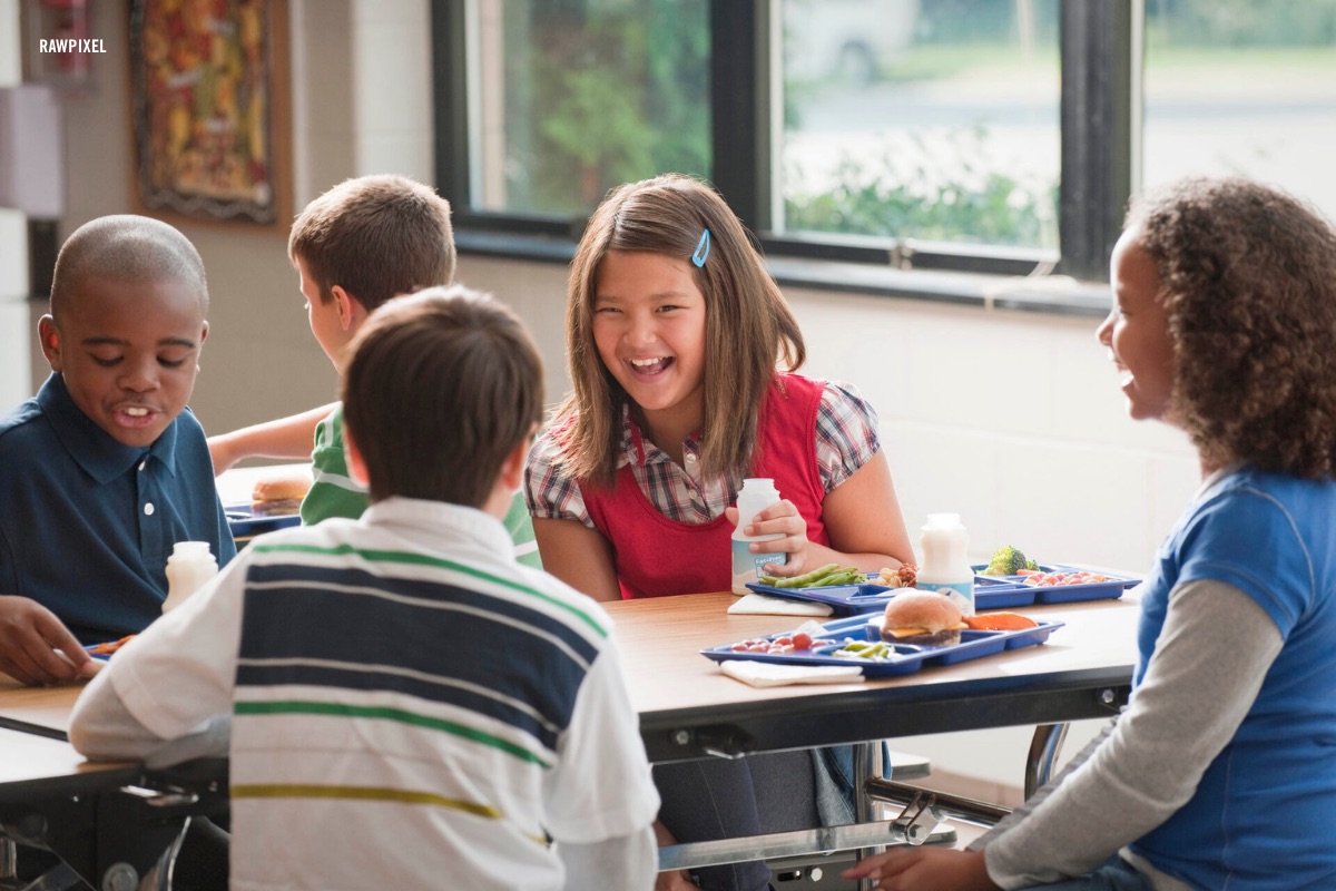 Students laughing together over lunch in a school cafeteria