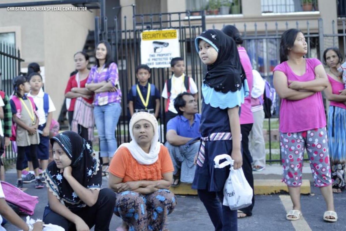 Families and children gathered on a sidewalk outside an apartment complex